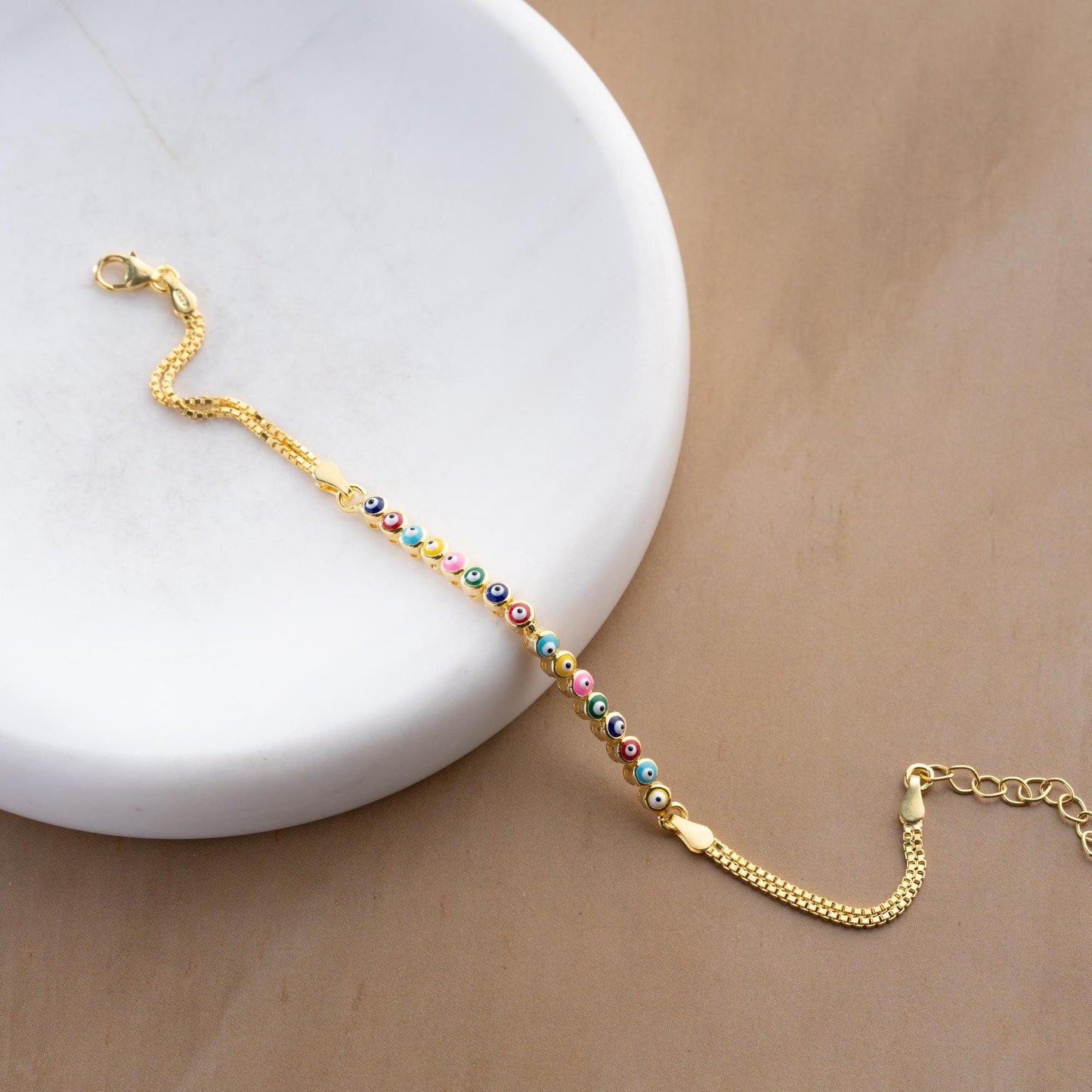 Vibrant charm bracelet featuring multicolored evil eye designs, crafted in 925 Sterling Silver, available in silver and gold finishes, perfect for gifting.