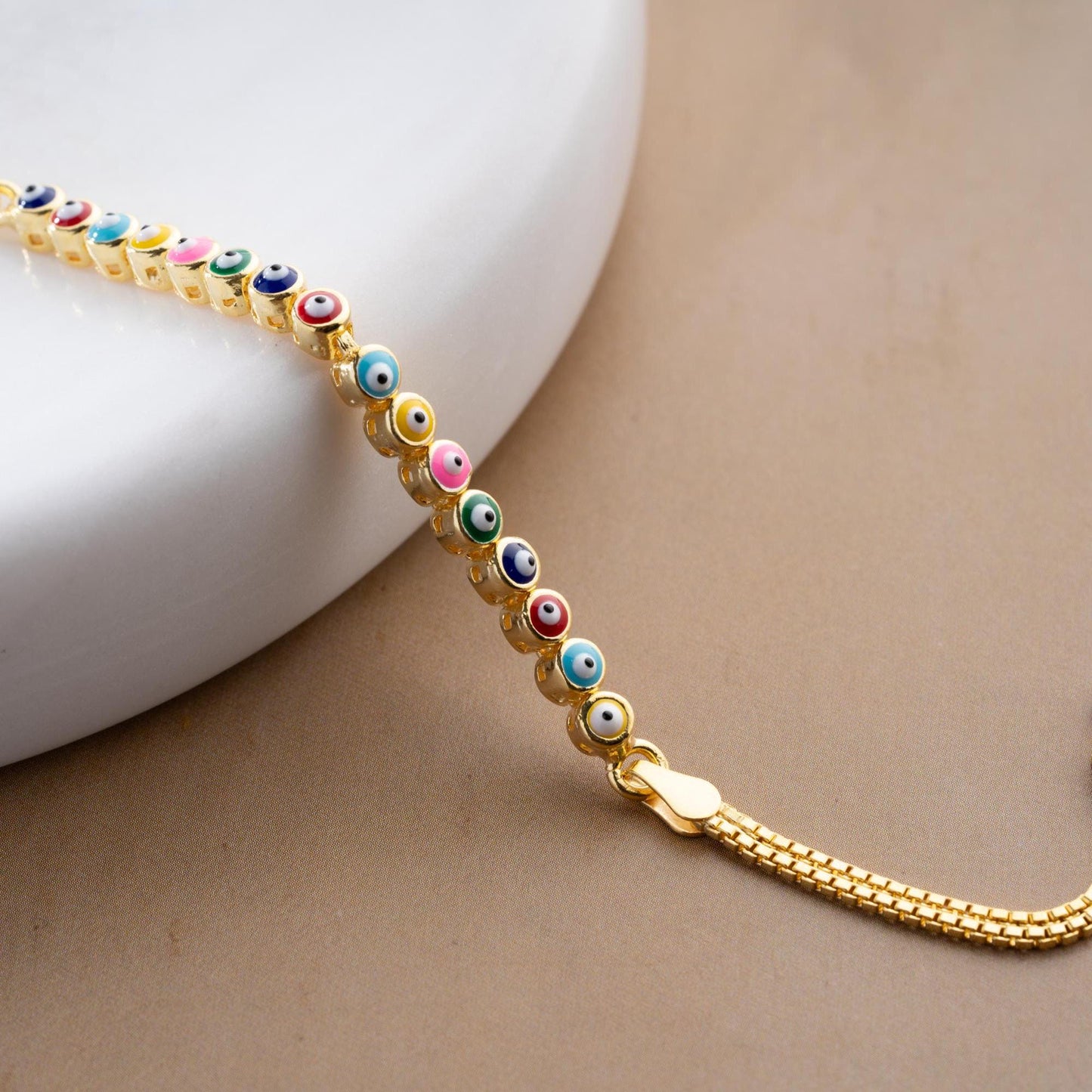 Vibrant charm bracelet featuring multicolored evil eye designs, crafted in 925 Sterling Silver, available in silver and gold finishes, perfect for gifting.