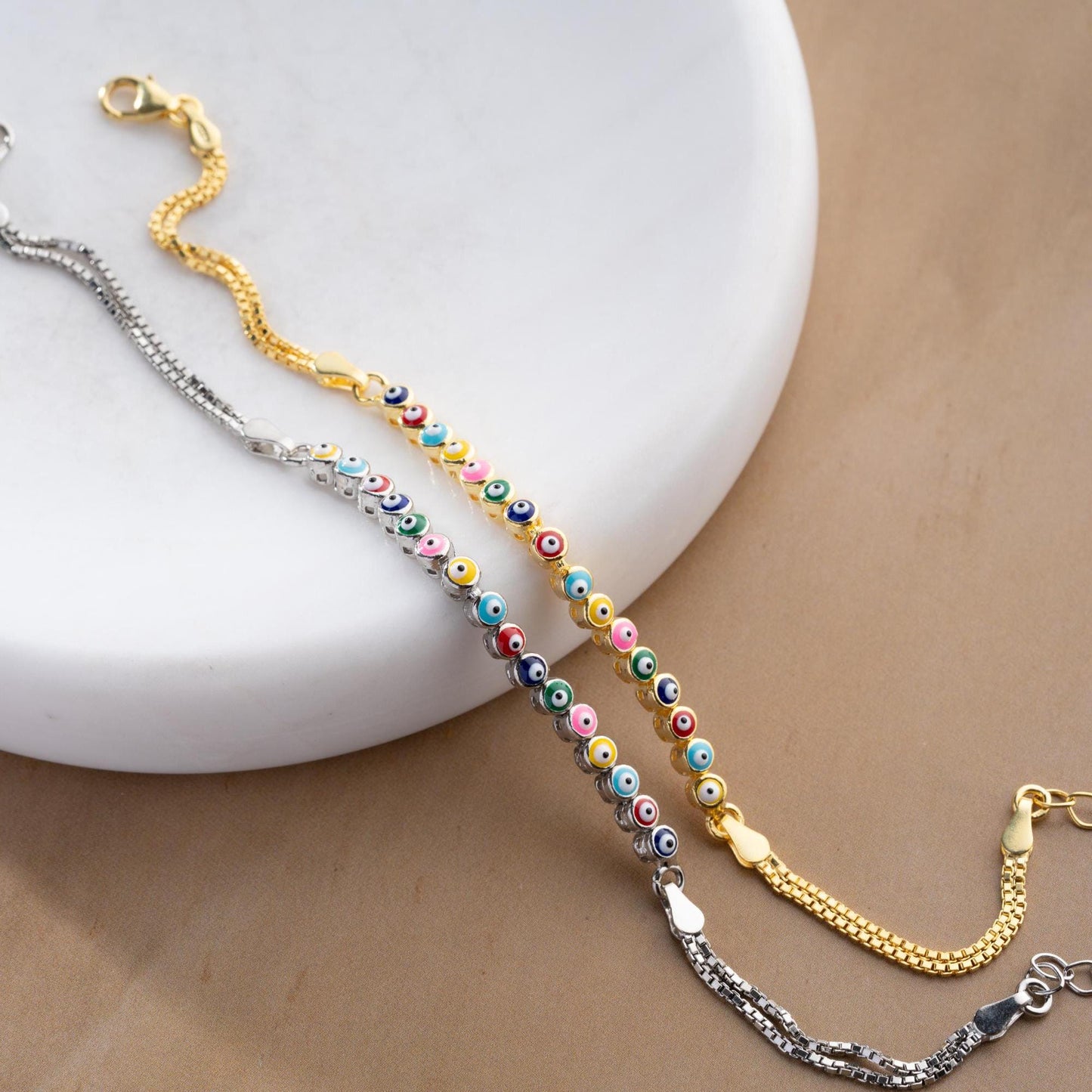 Vibrant charm bracelet featuring multicolored evil eye designs, crafted in 925 Sterling Silver, available in silver and gold finishes, perfect for gifting.