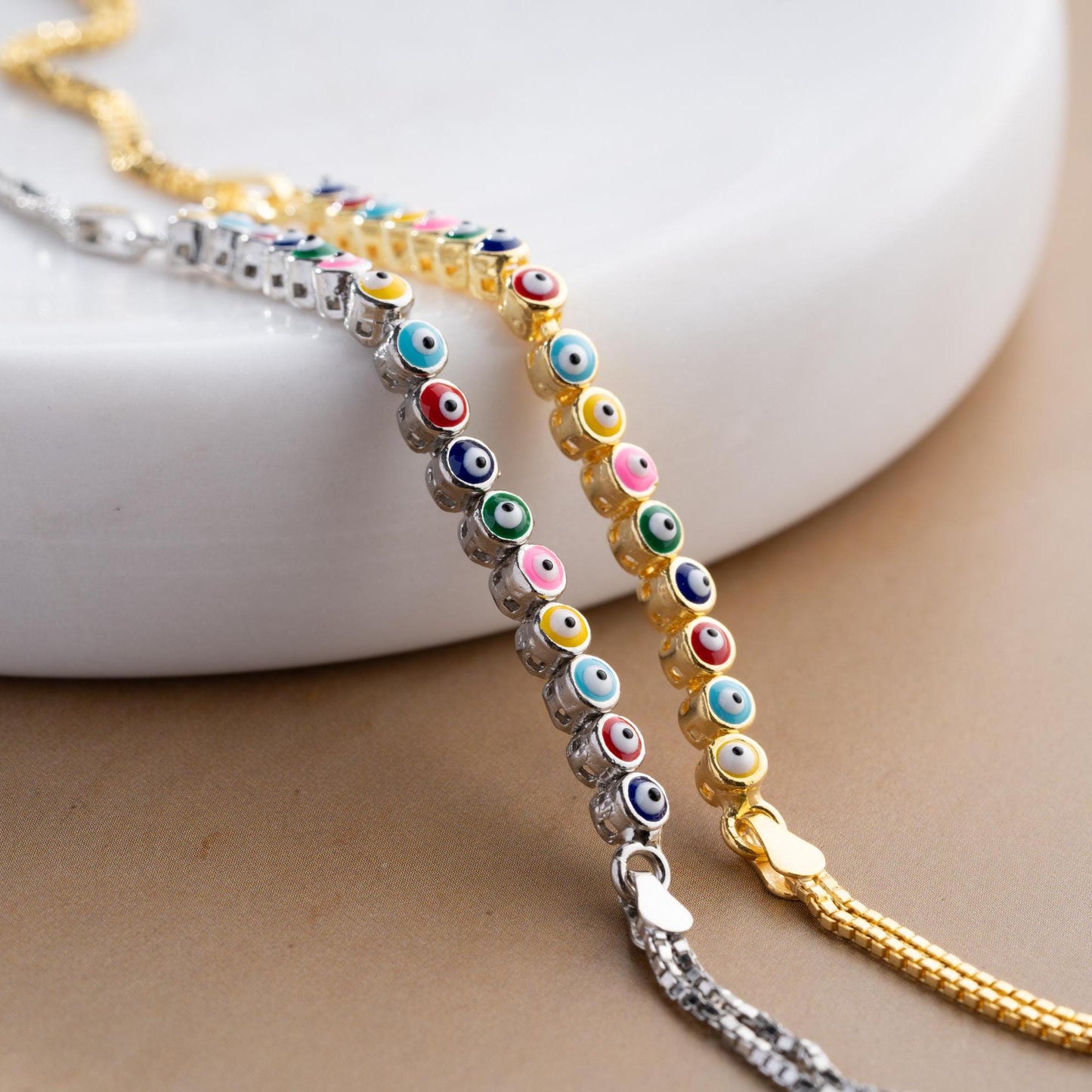 Vibrant charm bracelet featuring multicolored evil eye designs, crafted in 925 Sterling Silver, available in silver and gold finishes, perfect for gifting.