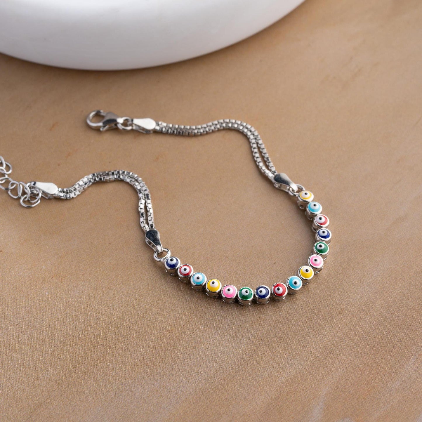 Vibrant charm bracelet featuring multicolored evil eye designs, crafted in 925 Sterling Silver, available in silver and gold finishes, perfect for gifting.