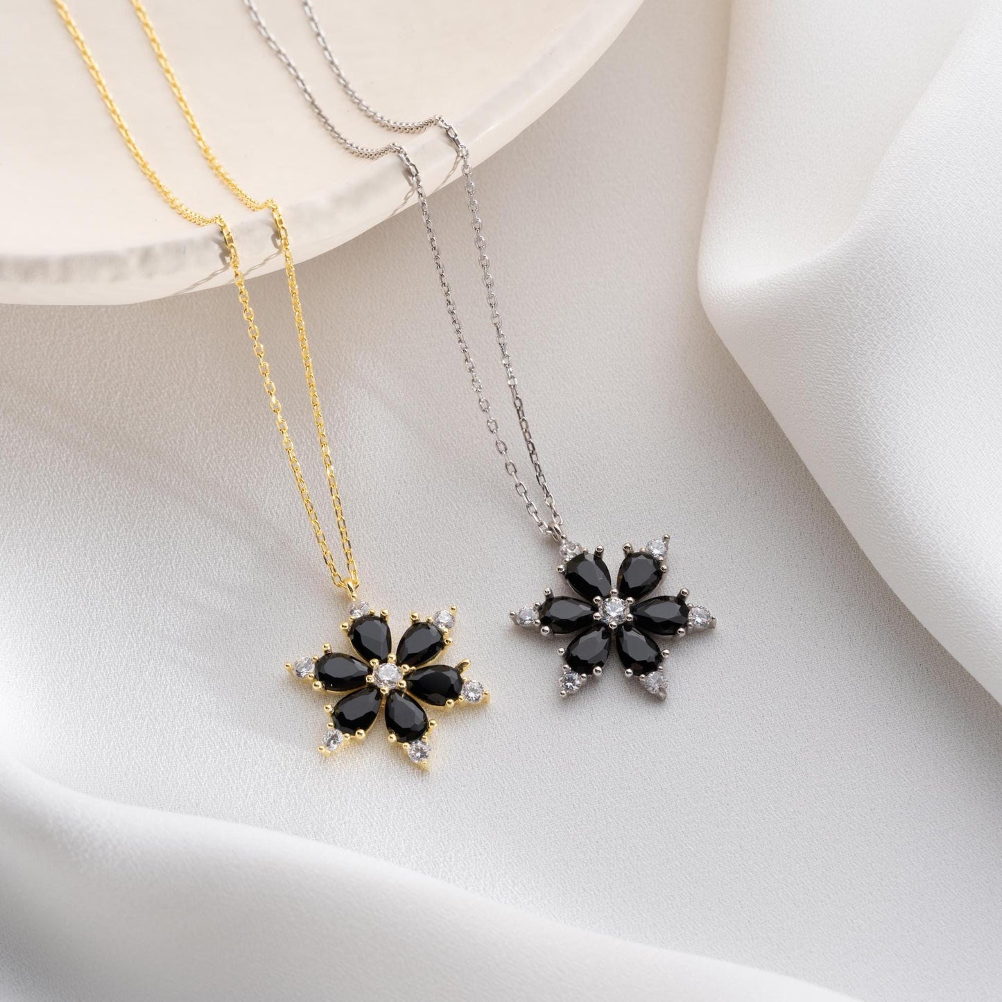 Elegant black flower necklace with genuine zircon stones, available in 925 sterling silver and 14K gold plated options, displayed on a white satin background.