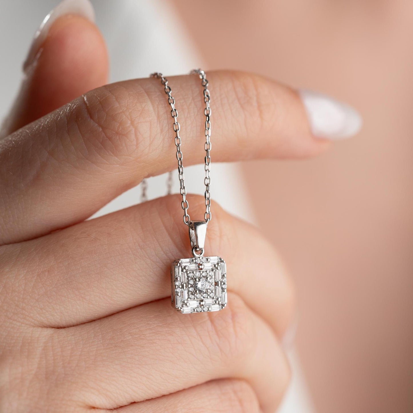 Square pendant necklace with cubic zirconia stones, available in 925 sterling silver and 14K gold plated options, displayed on a white satin background.