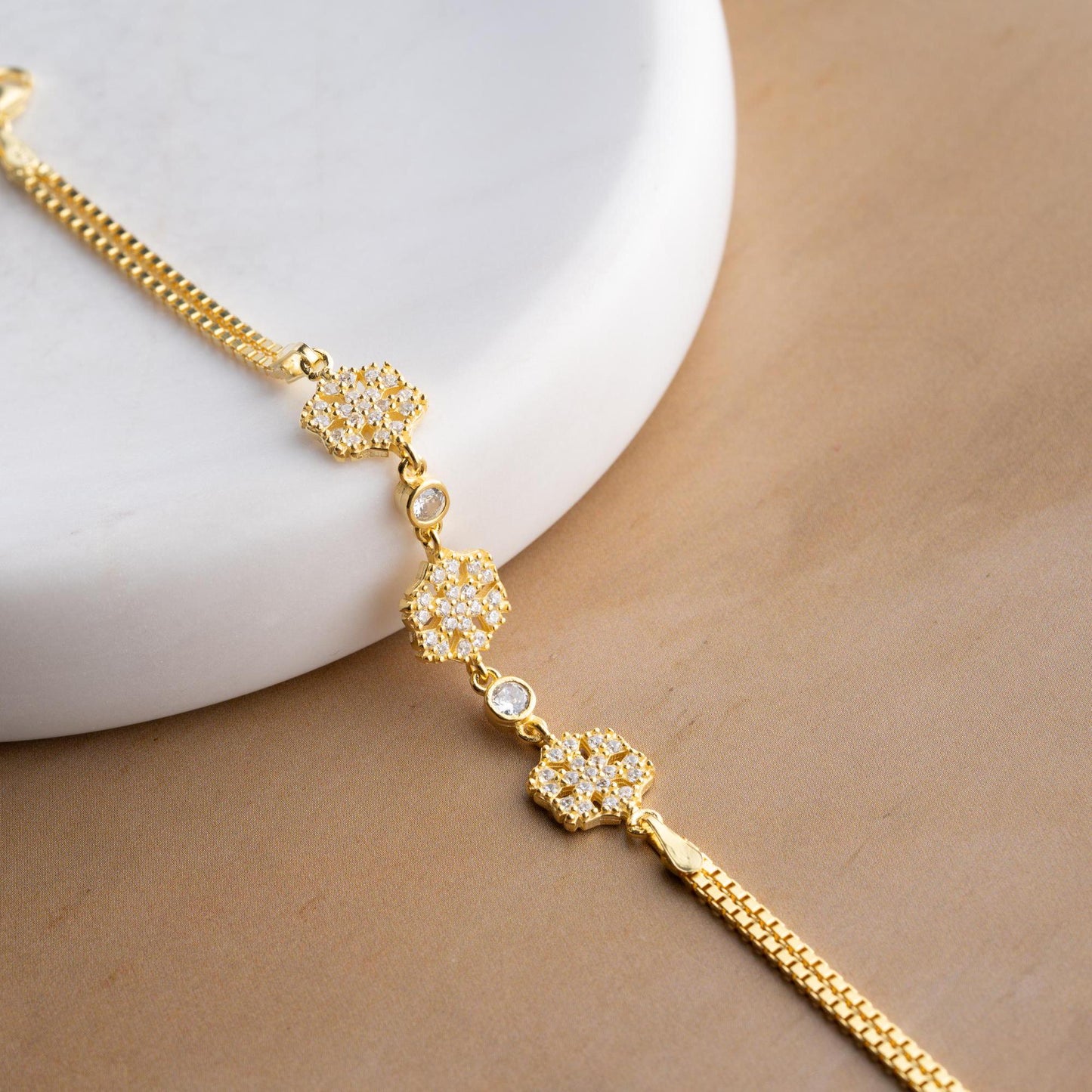 Elegant snowflake charm bracelet crafted in 925 Sterling Silver with cubic zirconia stones, available in silver and gold finishes, perfect for winter gifting.