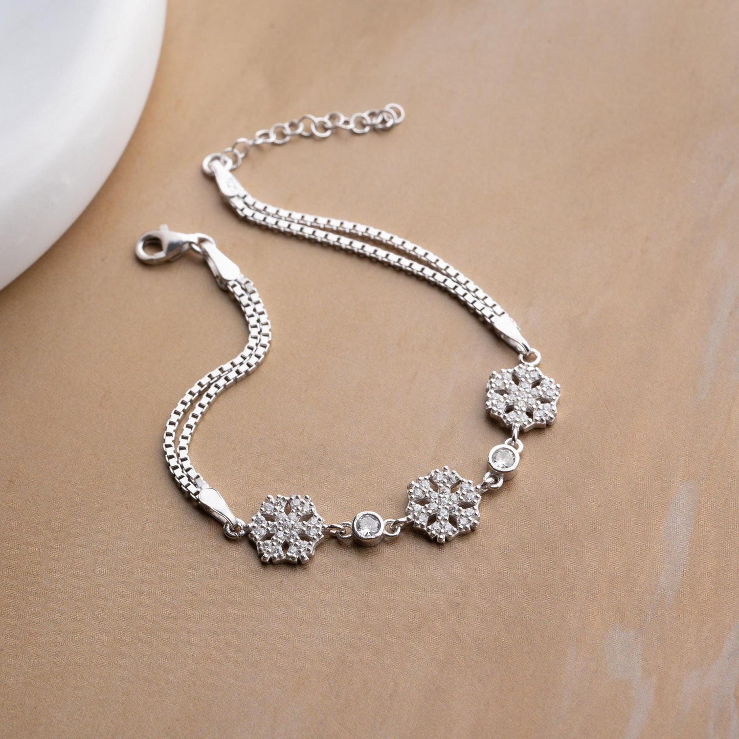 Elegant snowflake charm bracelet crafted in 925 Sterling Silver with cubic zirconia stones, available in silver and gold finishes, perfect for winter gifting.