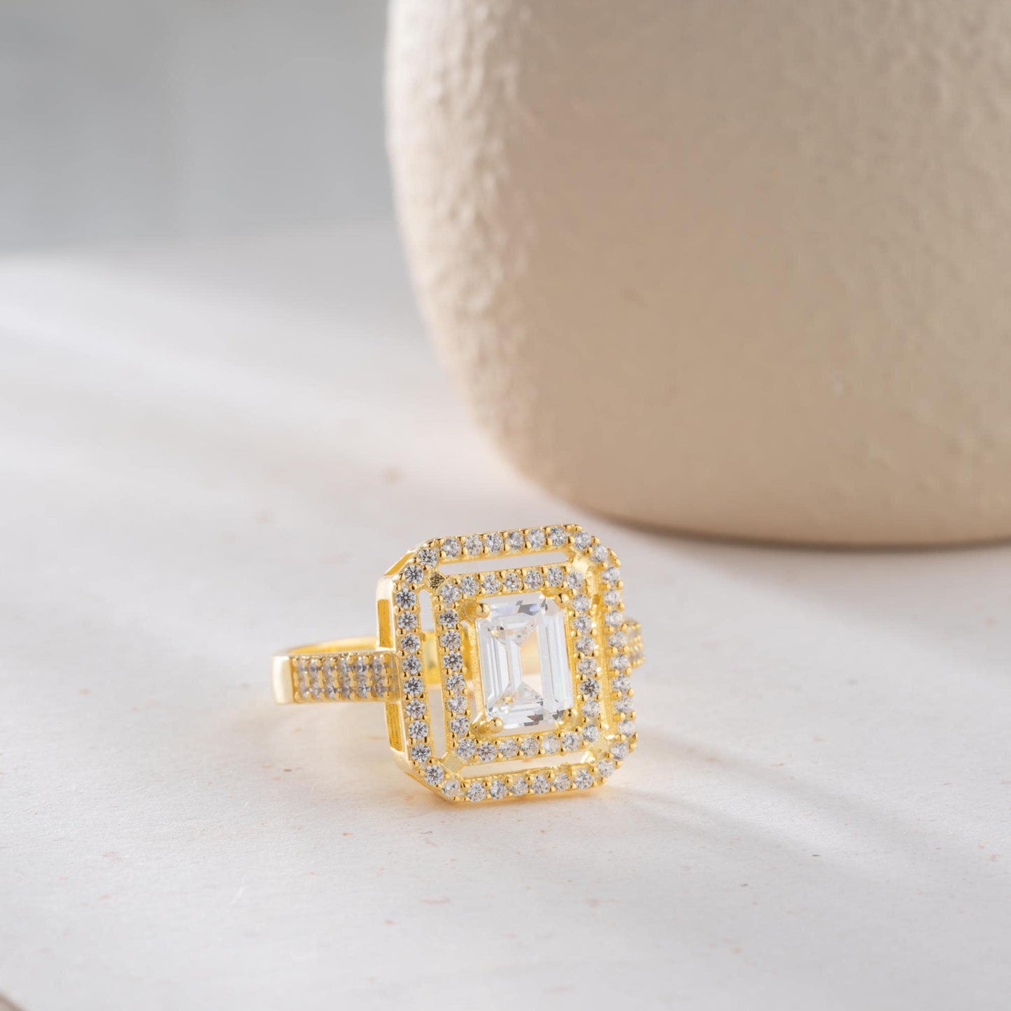 Elegant emerald cut double halo statement ring crafted in 925 sterling silver with cubic zirconia stones, available in silver and gold plated finishes.