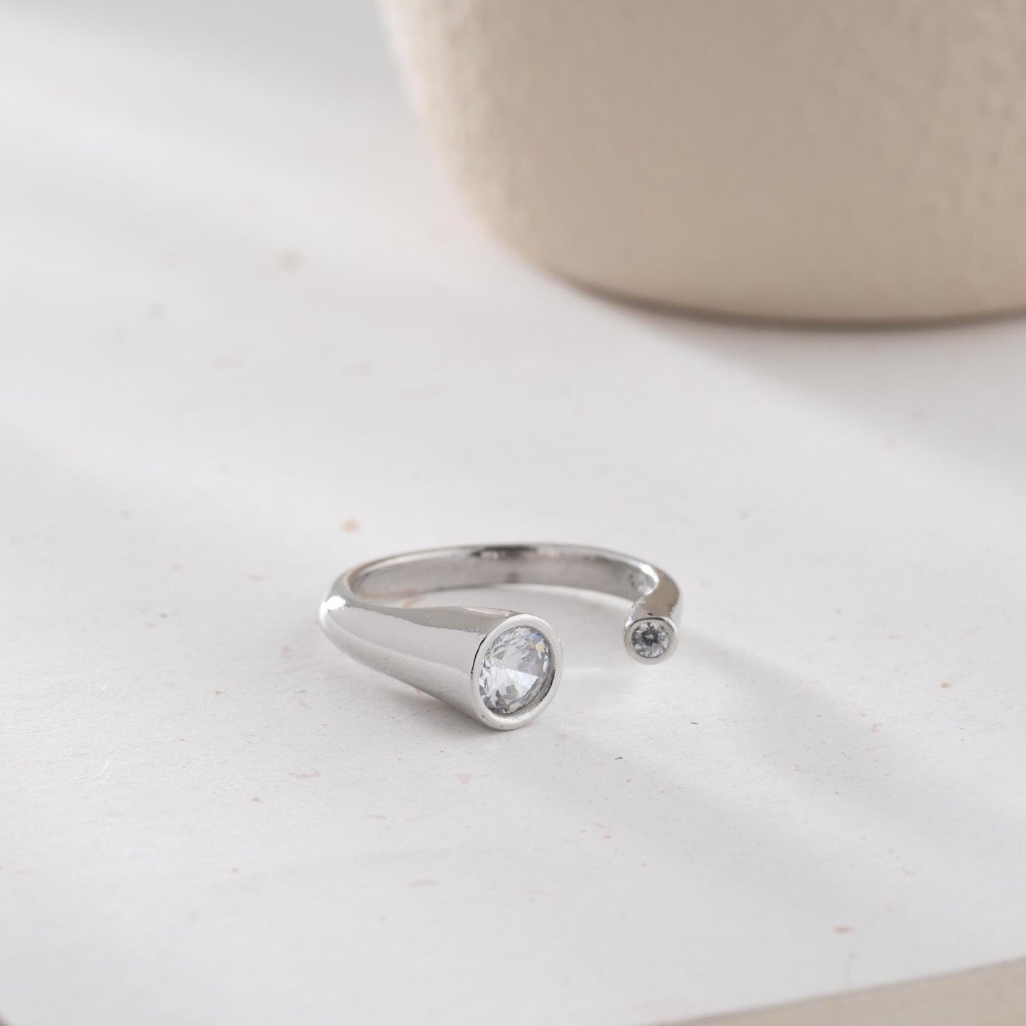 Elegant open ring with dual bezel-set zircon stones, crafted from 925 sterling silver and available in gold plated and silver finishes.