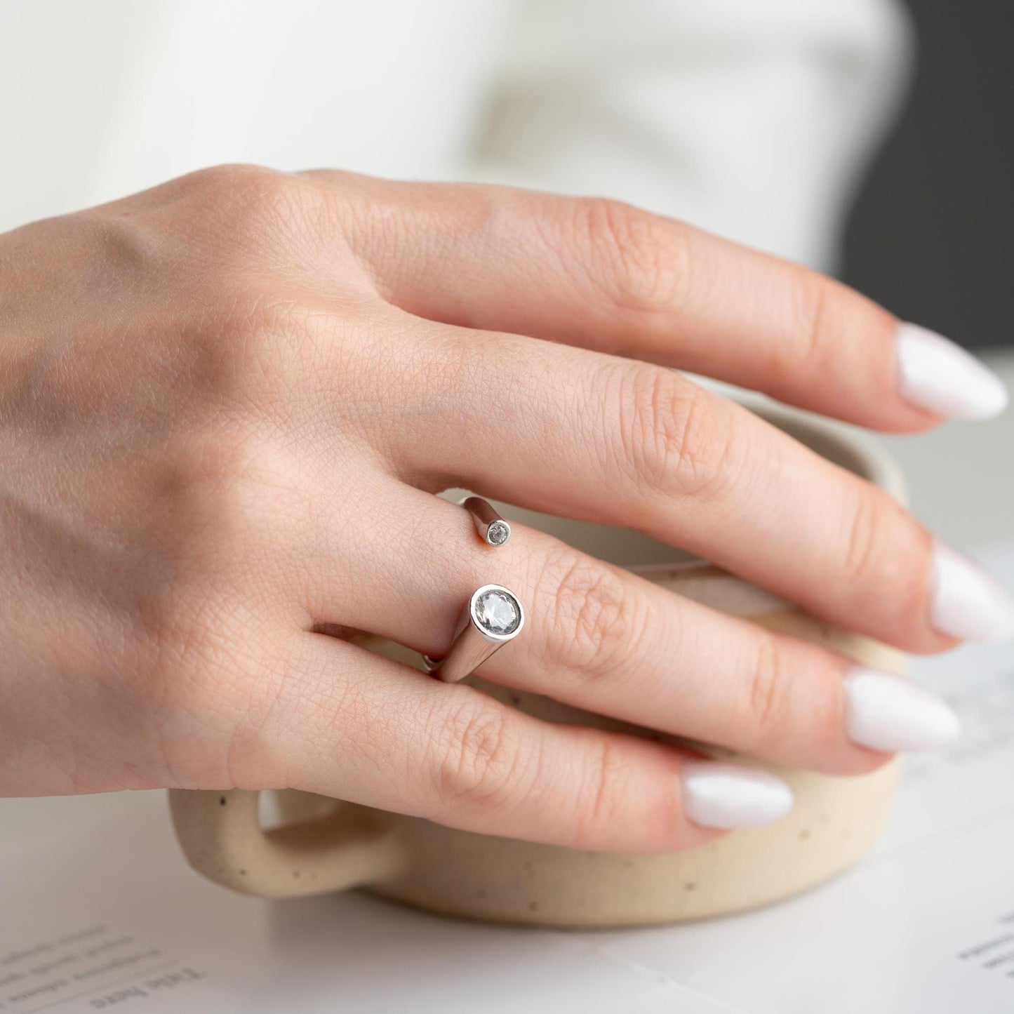 Elegant open ring with dual bezel-set zircon stones, crafted from 925 sterling silver and available in gold plated and silver finishes.