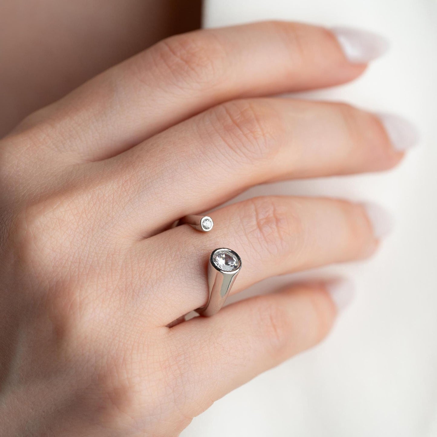 Elegant open ring with dual bezel-set zircon stones, crafted from 925 sterling silver and available in gold plated and silver finishes.