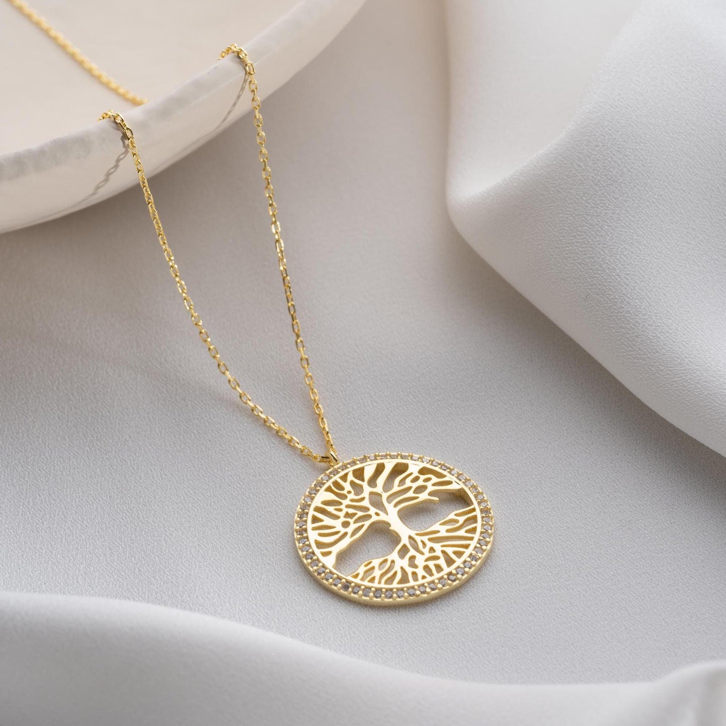 Tree of Life necklace with cubic zirconia stones, available in 925 sterling silver and 14K gold plated options, displayed on a white satin background.