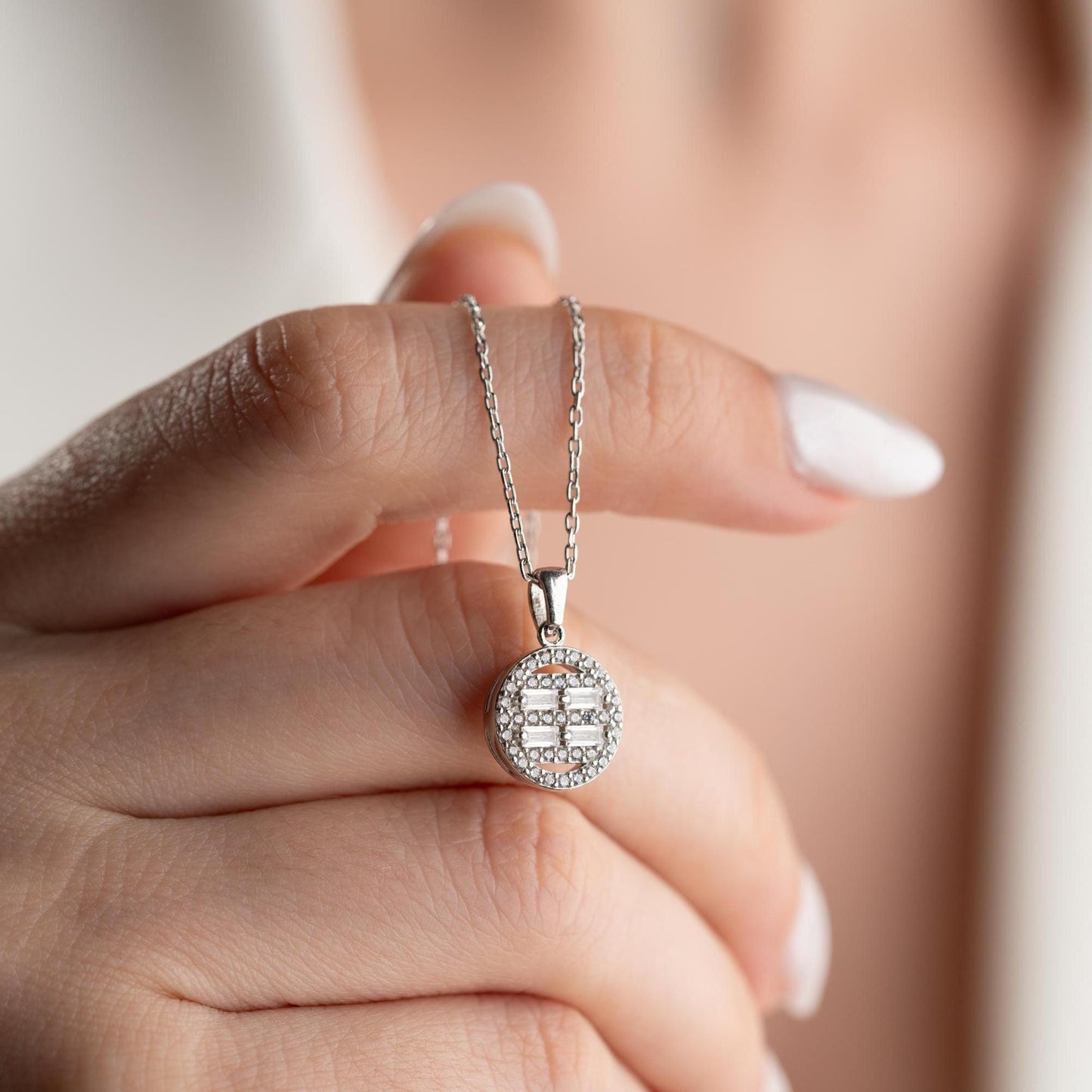 Round pendant necklace with cubic zirconia stones, available in 925 sterling silver and 14K gold plated options, displayed on a white satin background.