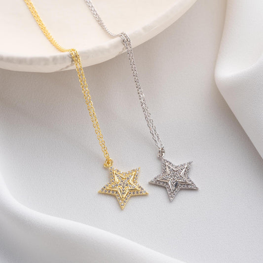 Star pendant necklace with cubic zirconia stones, available in 925 sterling silver and 14K gold plated options, displayed on a white satin background.