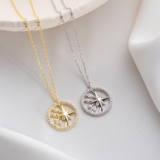 North Star pendant necklace with cubic zirconia stones, available in 925 sterling silver and 14K gold plated options, displayed on a white satin background