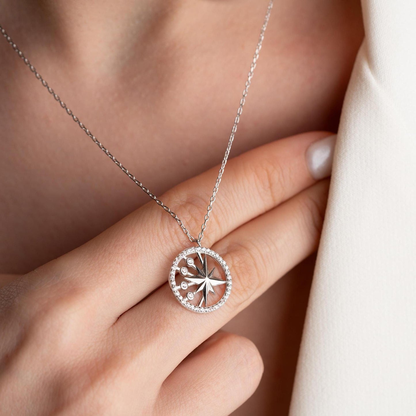 North Star pendant necklace with cubic zirconia stones, available in 925 sterling silver and 14K gold plated options, displayed on a white satin background
