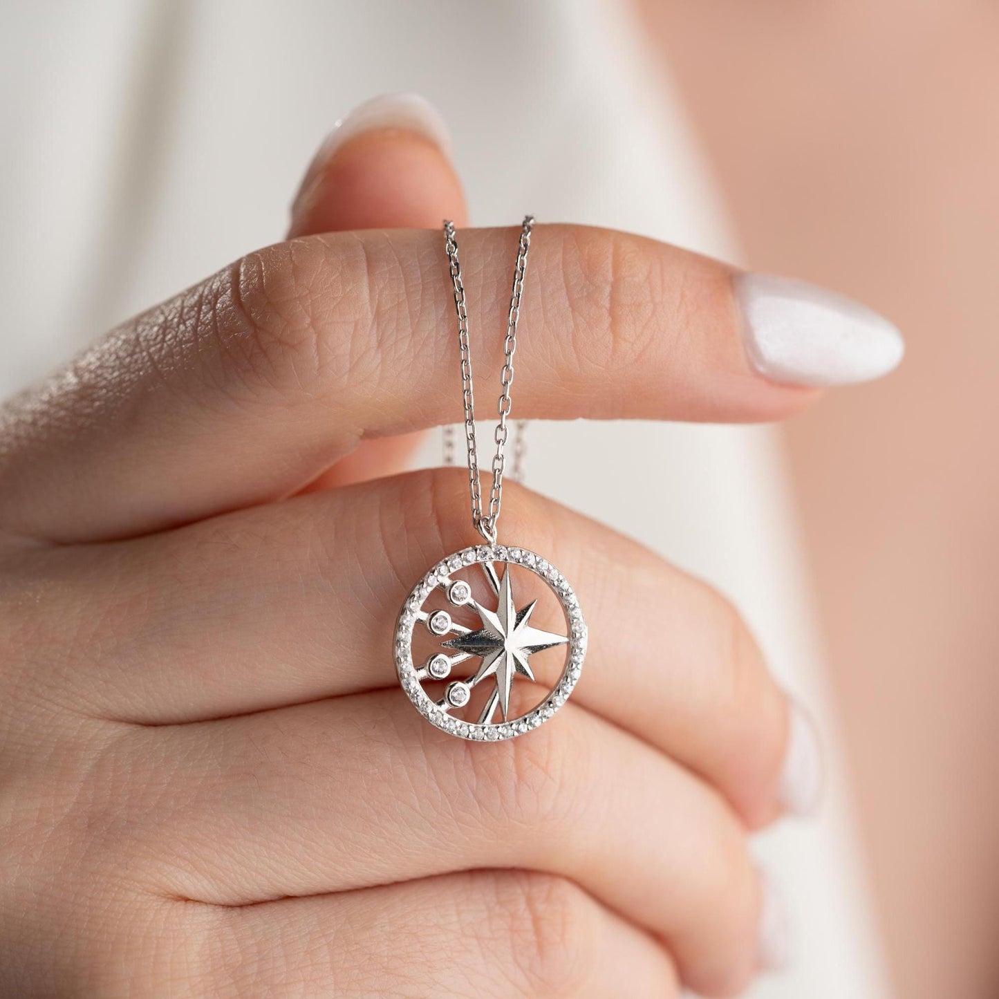 North Star pendant necklace with cubic zirconia stones, available in 925 sterling silver and 14K gold plated options, displayed on a white satin background