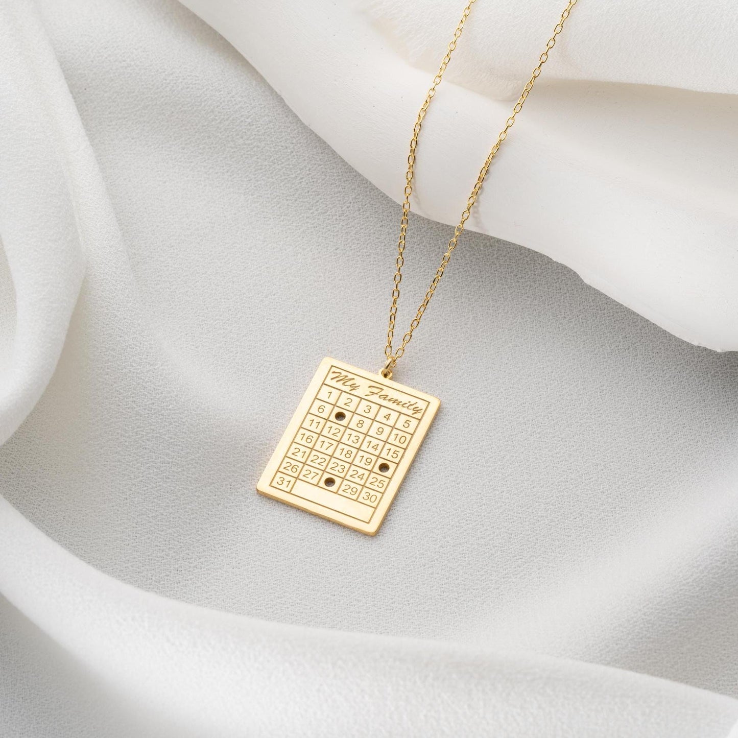 A personalized calendar necklace with a custom date engraving, available in sterling silver and gold plated finishes. The perfect anniversary, birthday, or wedding gift for her.