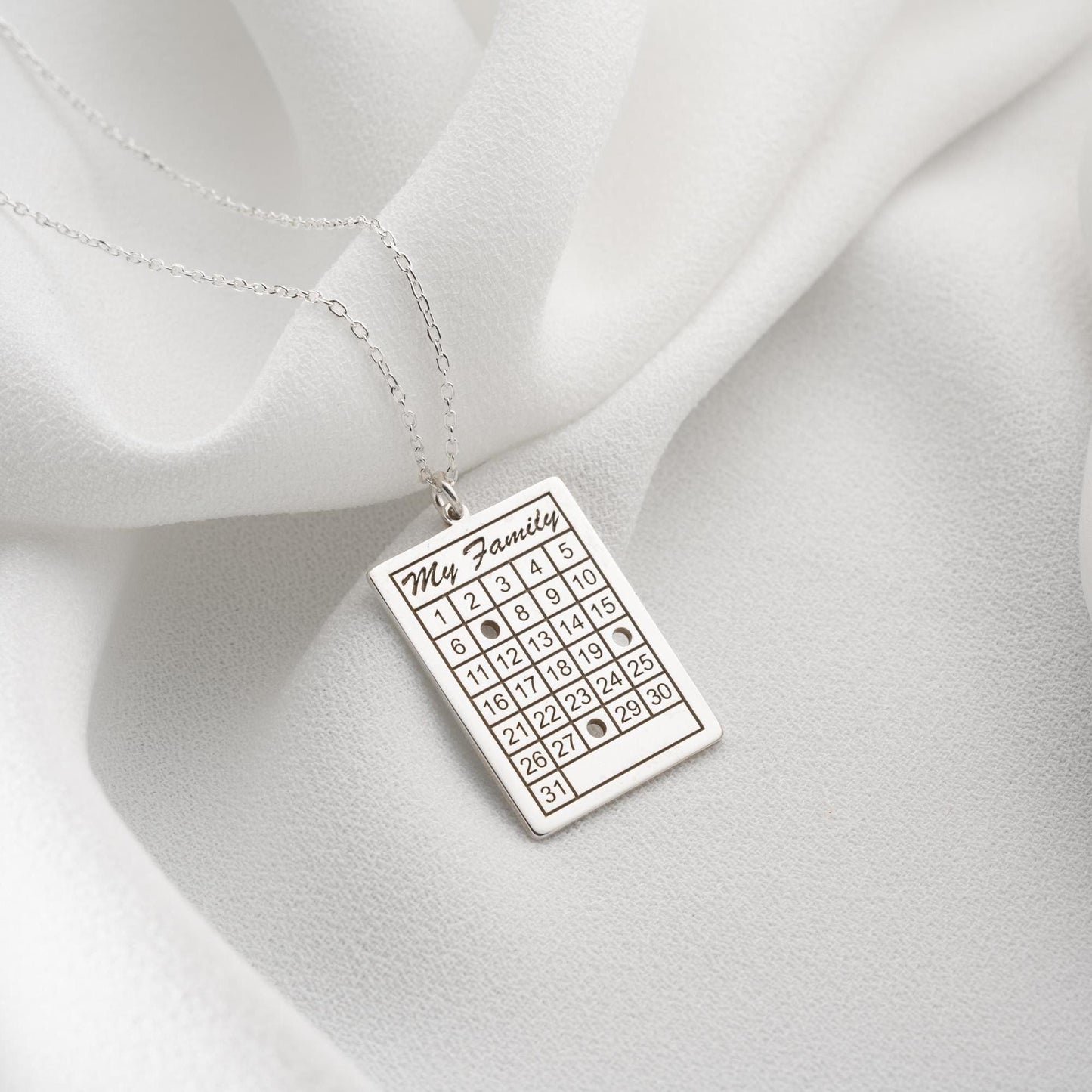 A personalized calendar necklace with a custom date engraving, available in sterling silver and gold plated finishes. The perfect anniversary, birthday, or wedding gift for her.