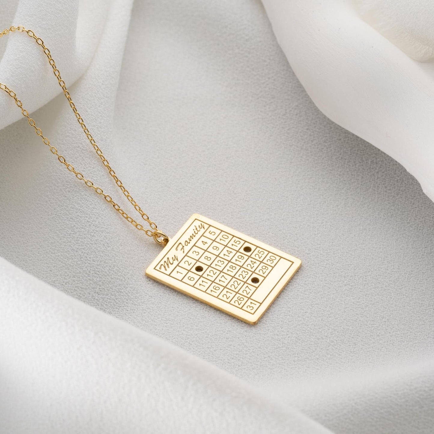 A personalized calendar necklace with a custom date engraving, available in sterling silver and gold plated finishes. The perfect anniversary, birthday, or wedding gift for her.