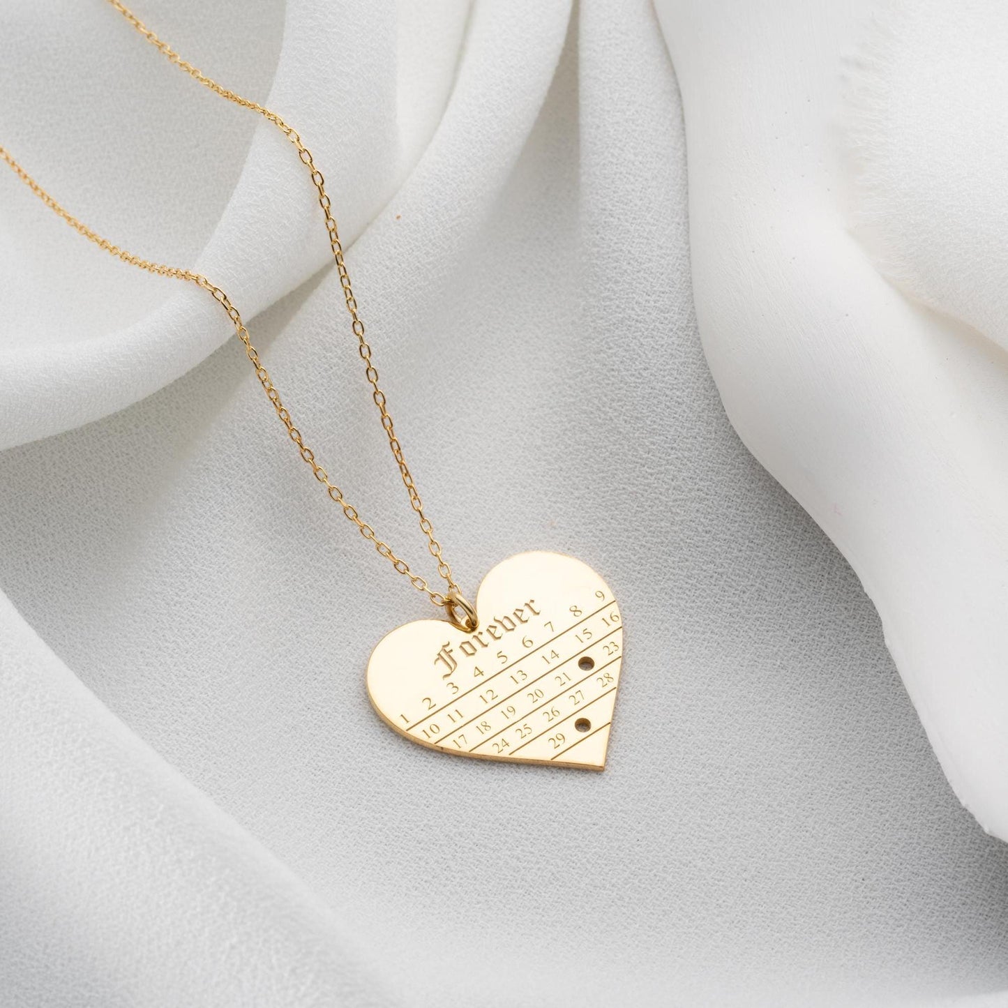 A personalized heart-shaped calendar necklace with a custom date engraving, available in sterling silver and gold plated finishes. Perfect for anniversaries, weddings, or Valentine's Day.