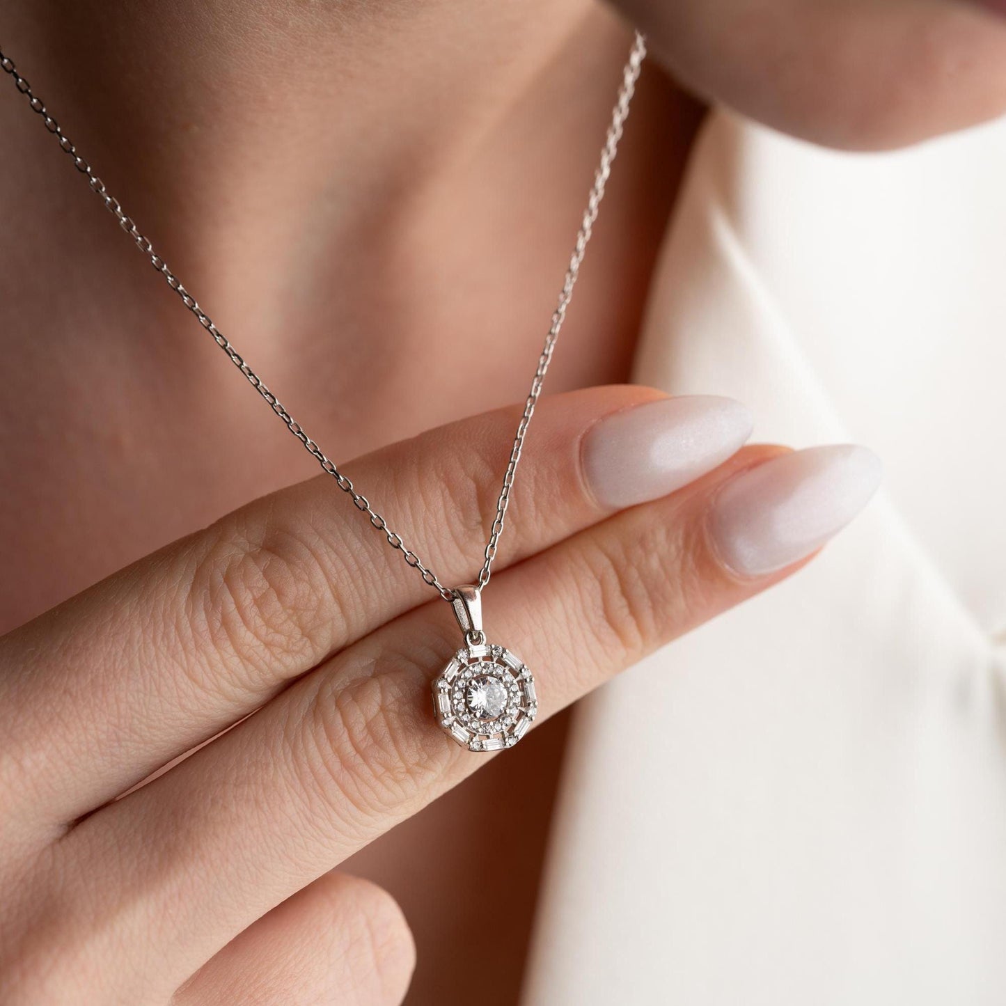 Halo pendant necklace with cubic zirconia stones, available in 925 sterling silver and 14K gold plated options, displayed on a white satin background.