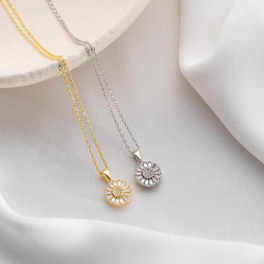 Sunburst pendant necklace with cubic zirconia, available in 925 sterling silver and 14K gold plated options, displayed on a soft satin background