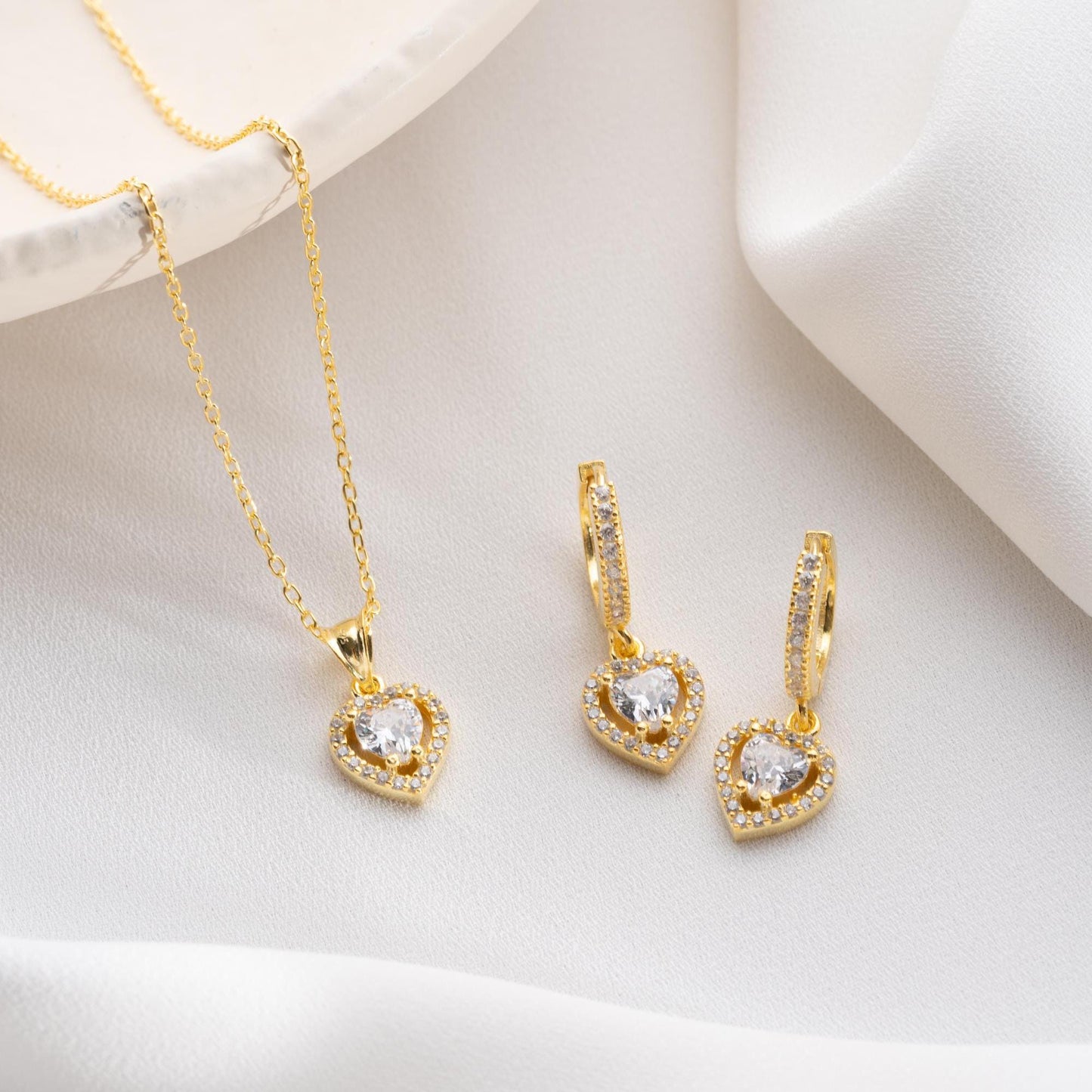 Heart pendant necklace and earrings set, crafted in 925 sterling silver with cubic zirconia stones, displayed on a soft satin background