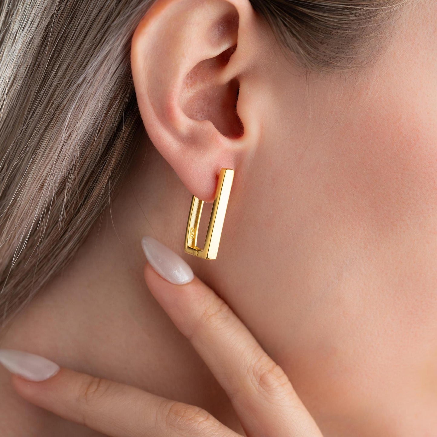 Minimalist rectangular hoop earrings crafted from 925 sterling silver with a 14K gold plated option, displayed on a marble surface.