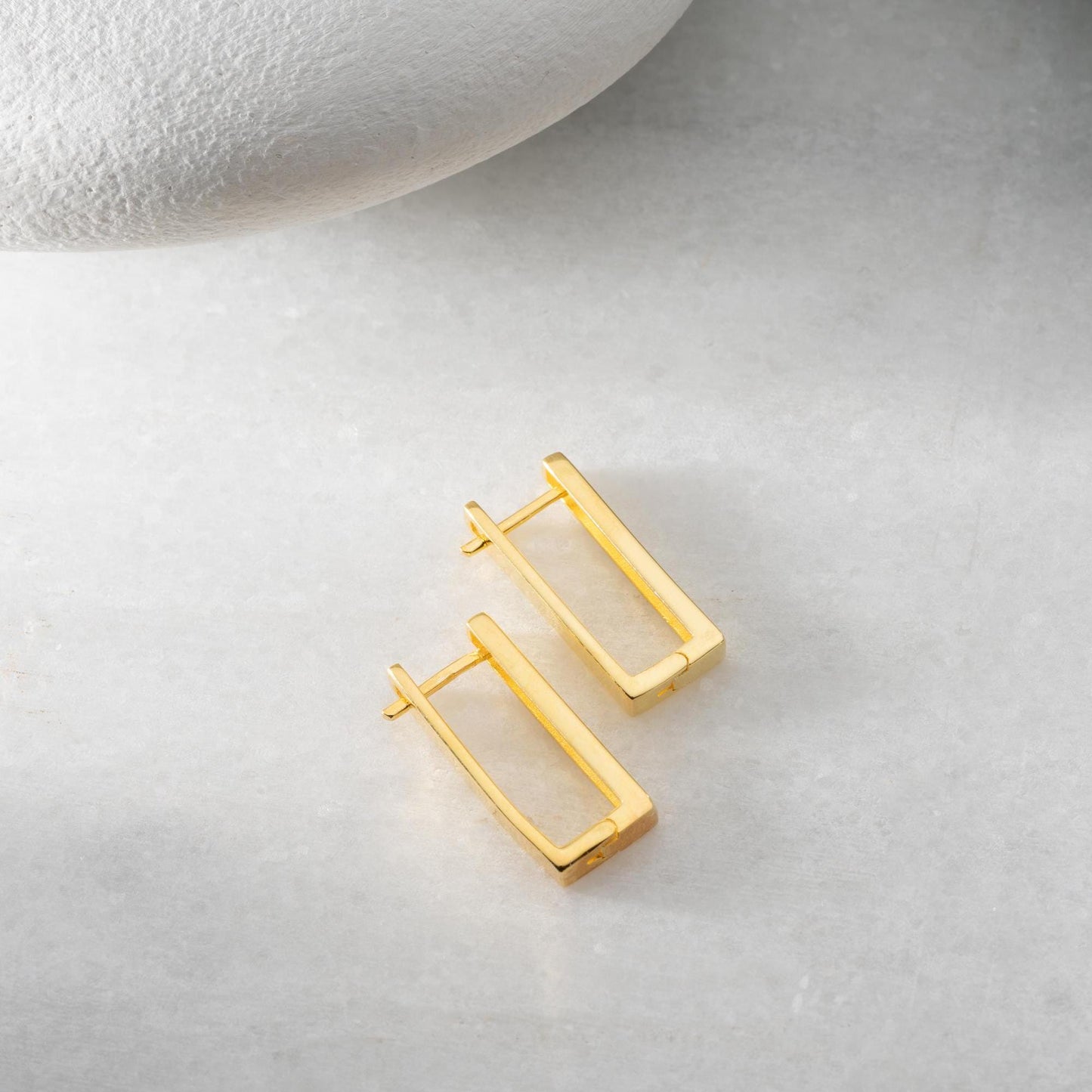 Minimalist rectangular hoop earrings crafted from 925 sterling silver with a 14K gold plated option, displayed on a marble surface.