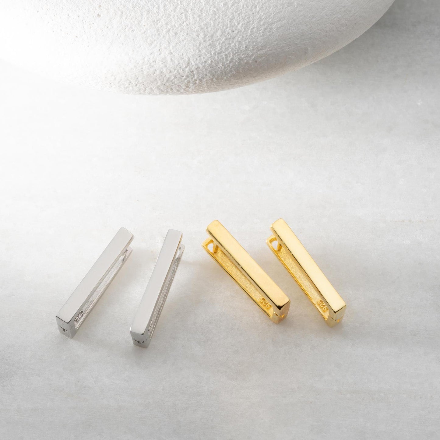 Minimalist rectangular hoop earrings crafted from 925 sterling silver with a 14K gold plated option, displayed on a marble surface.
