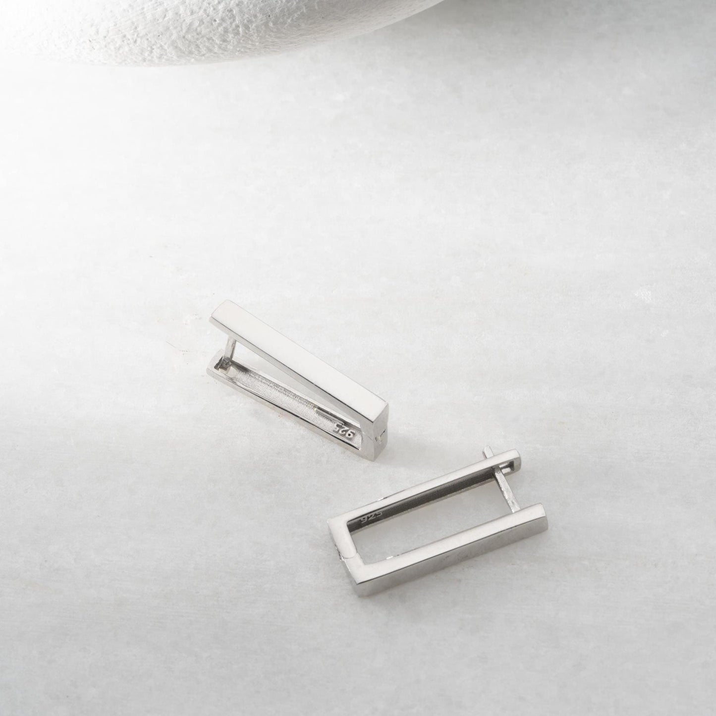 Minimalist rectangular hoop earrings crafted from 925 sterling silver with a 14K gold plated option, displayed on a marble surface.