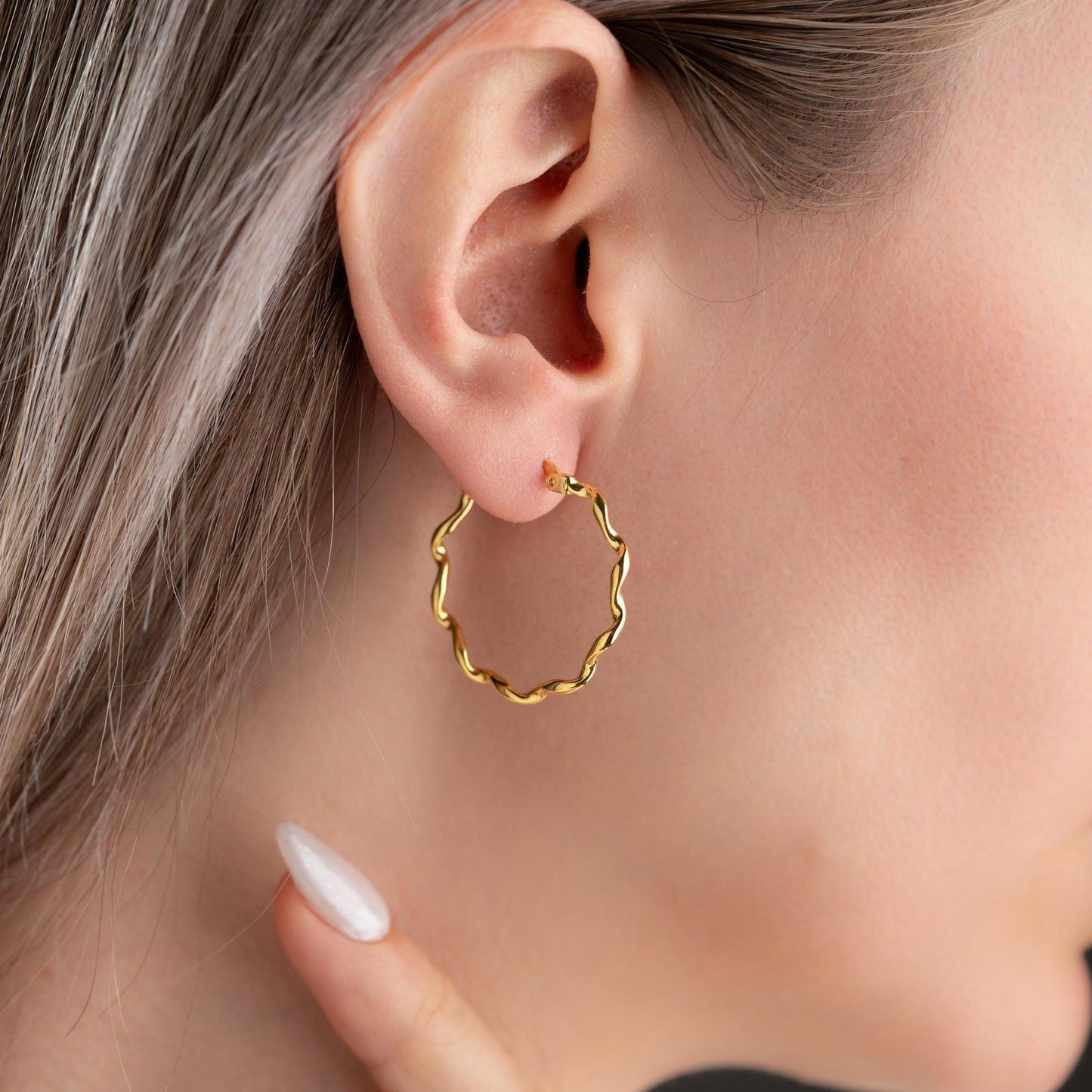 Wavy hoop earrings in 925 sterling silver and 14K gold plated options, displayed on a marble background