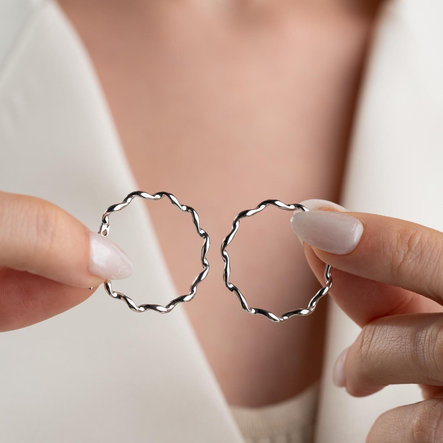 Wavy hoop earrings in 925 sterling silver and 14K gold plated options, displayed on a marble background