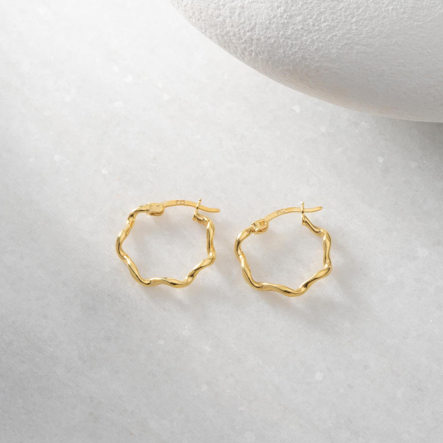 Wave hoop earrings crafted from 925 sterling silver with 14K gold plating option, displayed on a marble background.