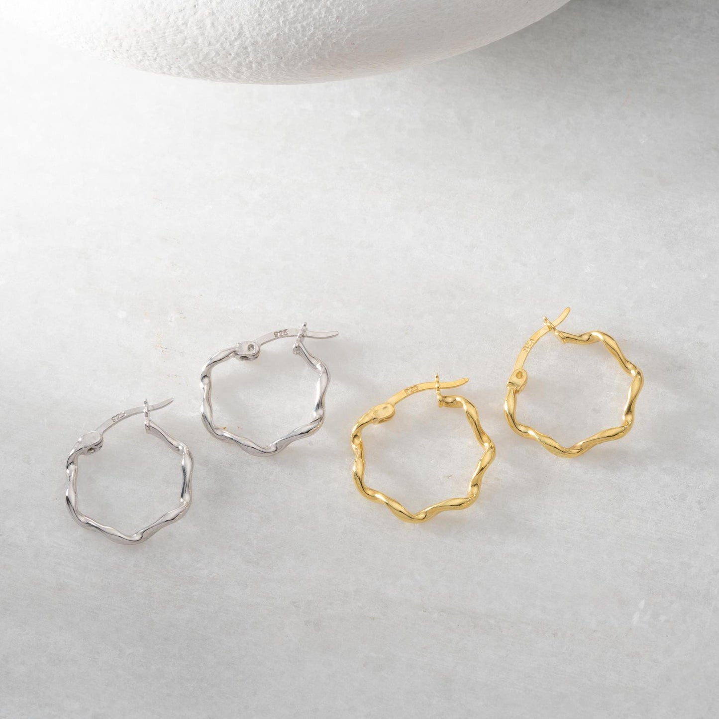 Wave hoop earrings crafted from 925 sterling silver with 14K gold plating option, displayed on a marble background.