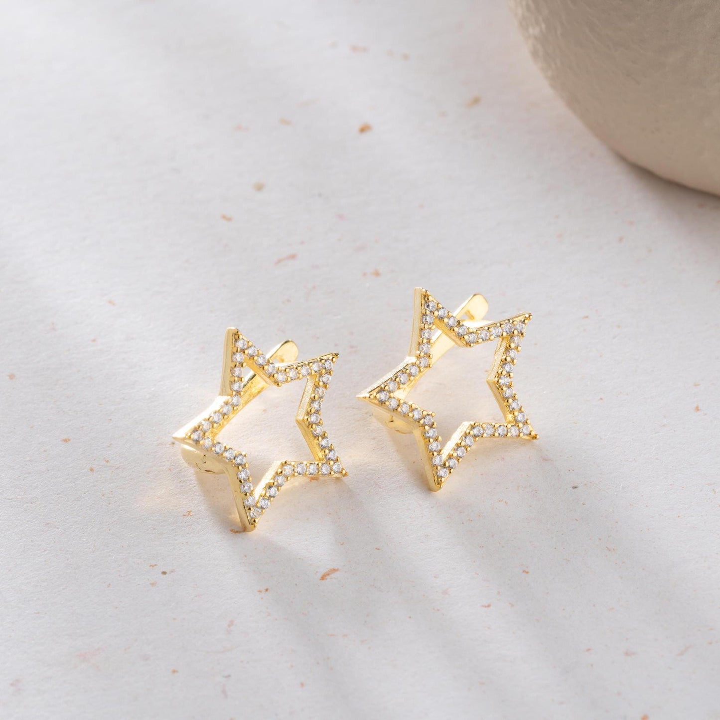 Star-shaped earrings with cubic zirconia stones, available in 925 sterling silver and 14K gold plated options, displayed on a minimalist background.