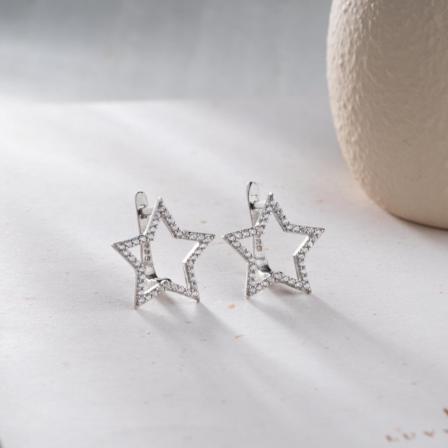 Star-shaped earrings with cubic zirconia stones, available in 925 sterling silver and 14K gold plated options, displayed on a minimalist background.