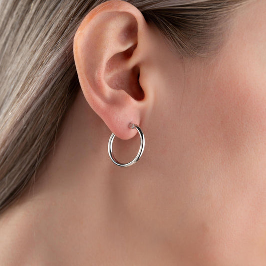 classic hoop earrings in 925 sterling silver and 14K gold plated options, featuring a minimalist polished design displayed on a marble background