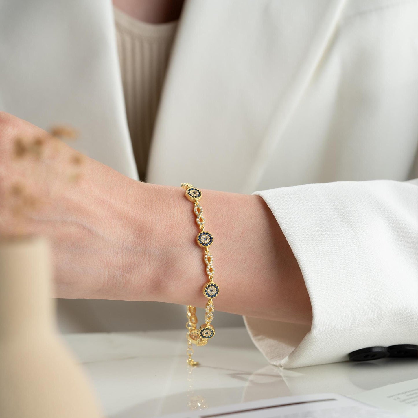 Infinity Evil Eye Bracelet with 925 Sterling Silver and 14K Gold Plated options, featuring blue evil eye accents, photographed in gold and silver variations.