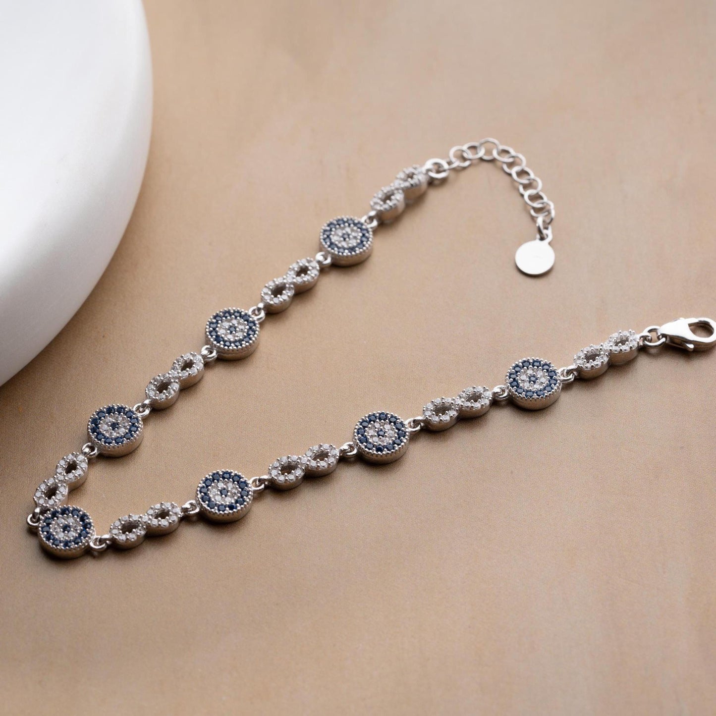 Infinity Evil Eye Bracelet with 925 Sterling Silver and 14K Gold Plated options, featuring blue evil eye accents, photographed in gold and silver variations.
