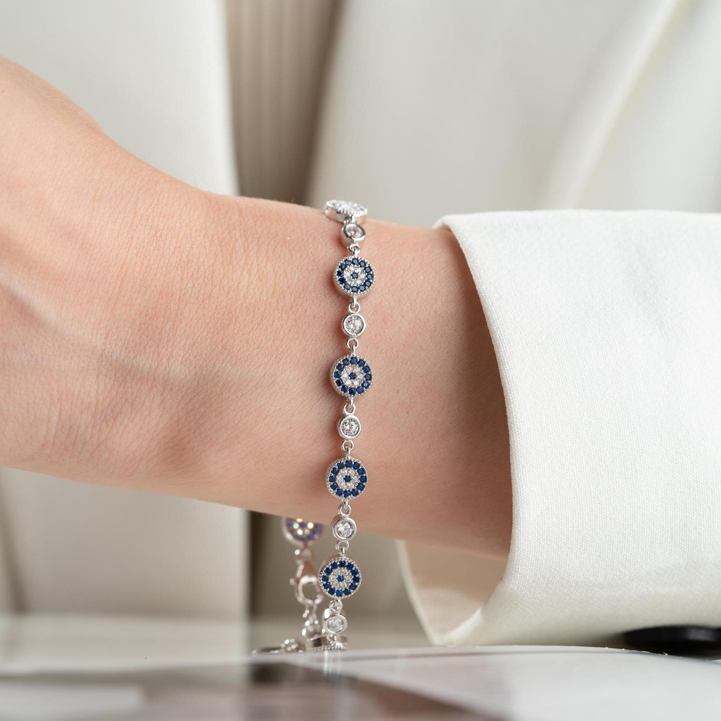 Evil Eye Charm Bracelet crafted in 925 Sterling Silver with cubic zirconia stones and intricate evil eye motifs, available in gold and silver finishes.