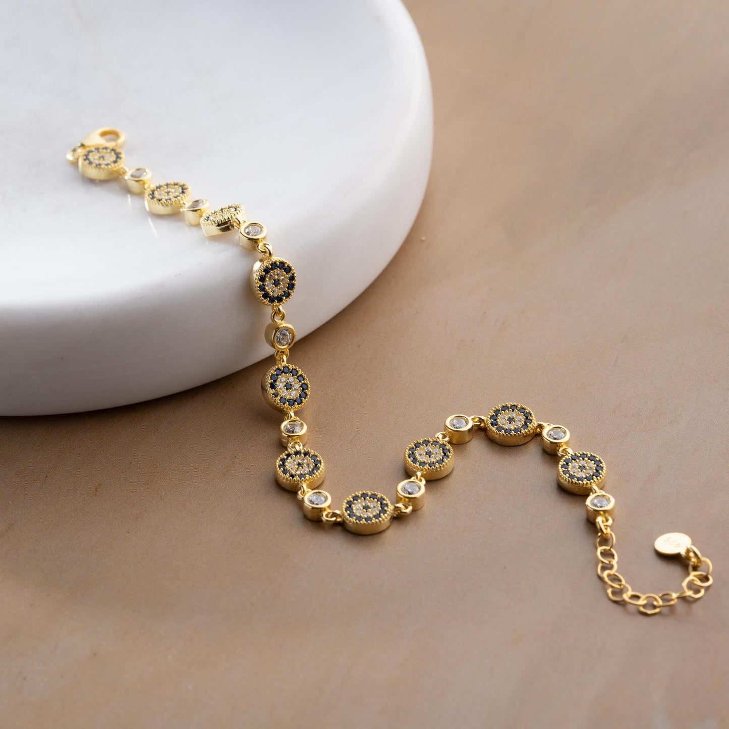 Evil Eye Charm Bracelet crafted in 925 Sterling Silver with cubic zirconia stones and intricate evil eye motifs, available in gold and silver finishes.