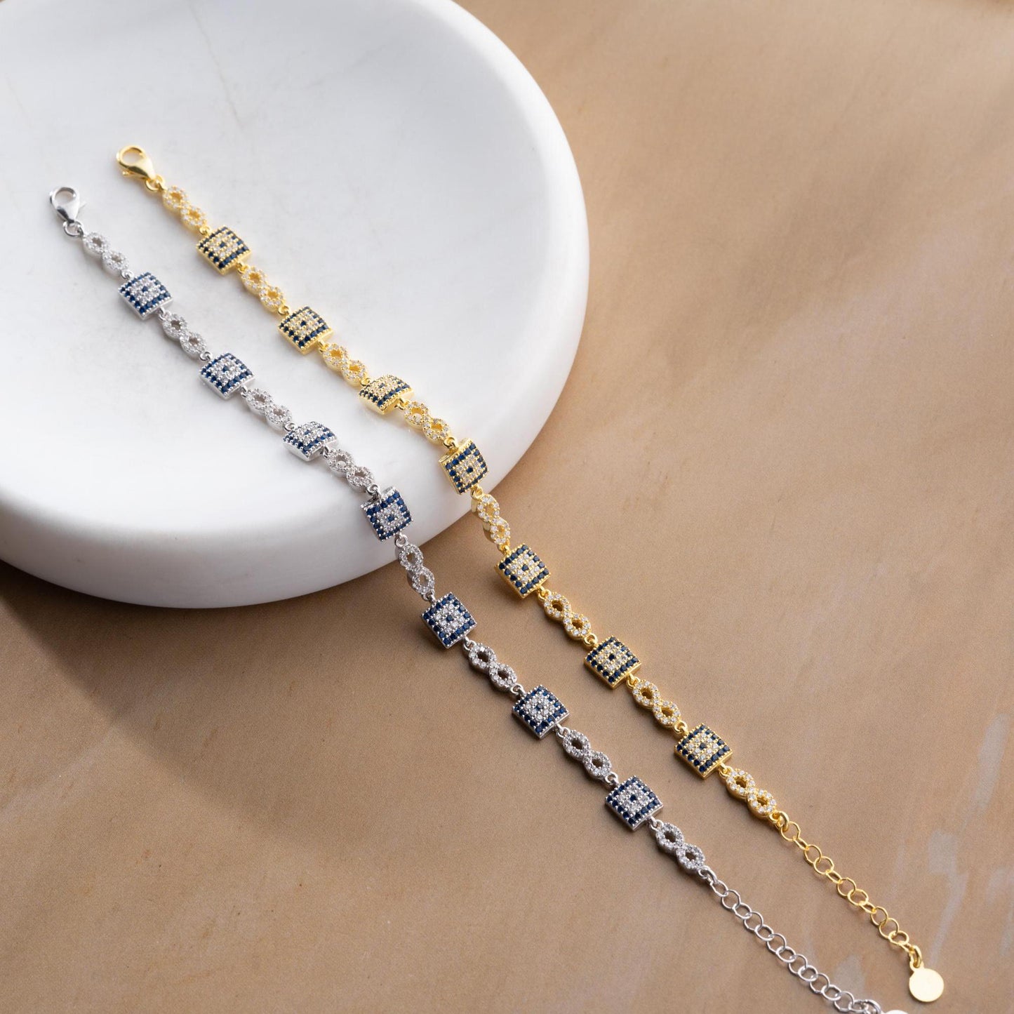 Elegant charm bracelet featuring square evil eye motifs and infinity symbols, crafted in 925 Sterling Silver with cubic zirconia stones, available in silver and gold finishes, perfect for festive gifting.
