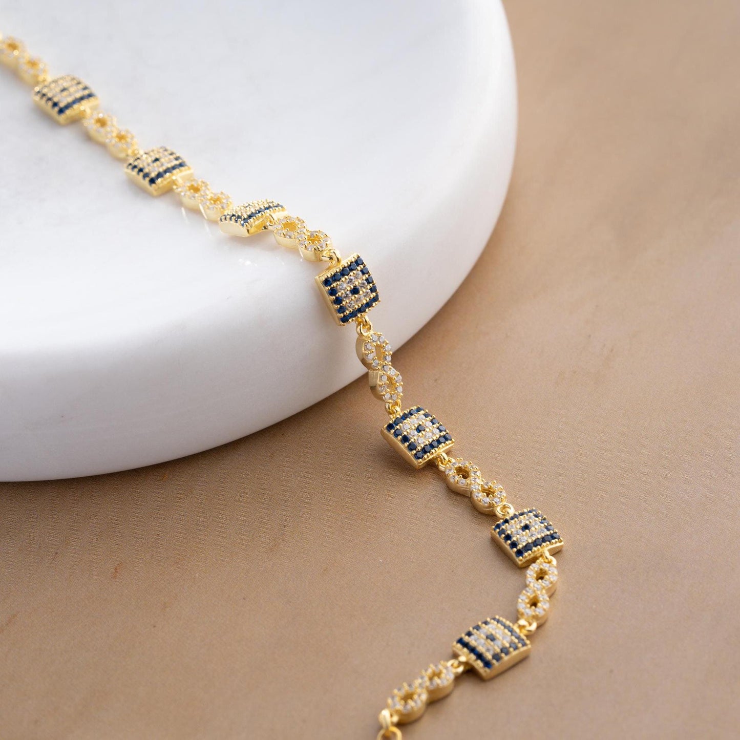 Elegant charm bracelet featuring square evil eye motifs and infinity symbols, crafted in 925 Sterling Silver with cubic zirconia stones, available in silver and gold finishes, perfect for festive gifting.