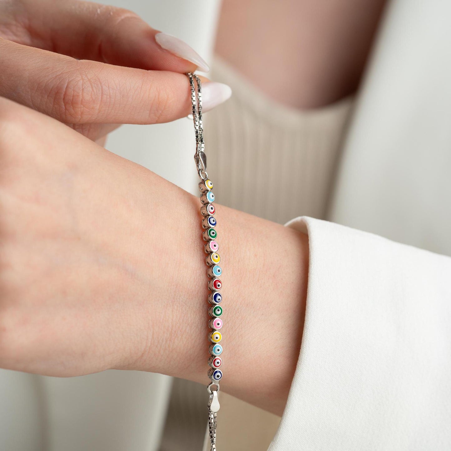 Vibrant charm bracelet featuring multicolored evil eye designs, crafted in 925 Sterling Silver, available in silver and gold finishes, perfect for gifting.