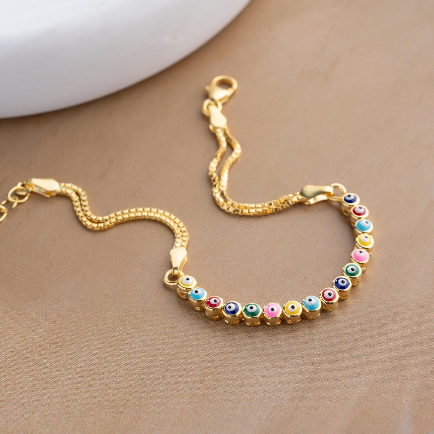 Vibrant charm bracelet featuring multicolored evil eye designs, crafted in 925 Sterling Silver, available in silver and gold finishes, perfect for gifting.