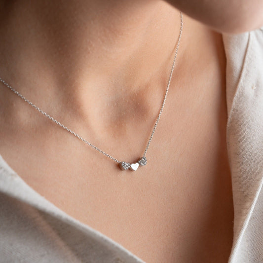 An exquisite silver necklace featuring three interlocking hearts, each heart intricately detailed with sparkling zircon stones, creating a luxurious and romantic piece perfect for gifting on special occasions or expressing love and affection.