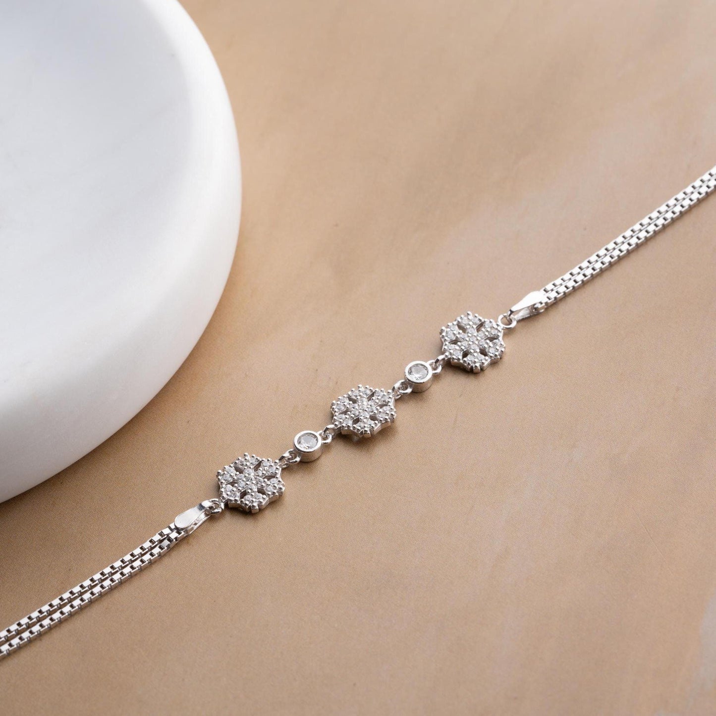 Elegant snowflake charm bracelet crafted in 925 Sterling Silver with cubic zirconia stones, available in silver and gold finishes, perfect for winter gifting.