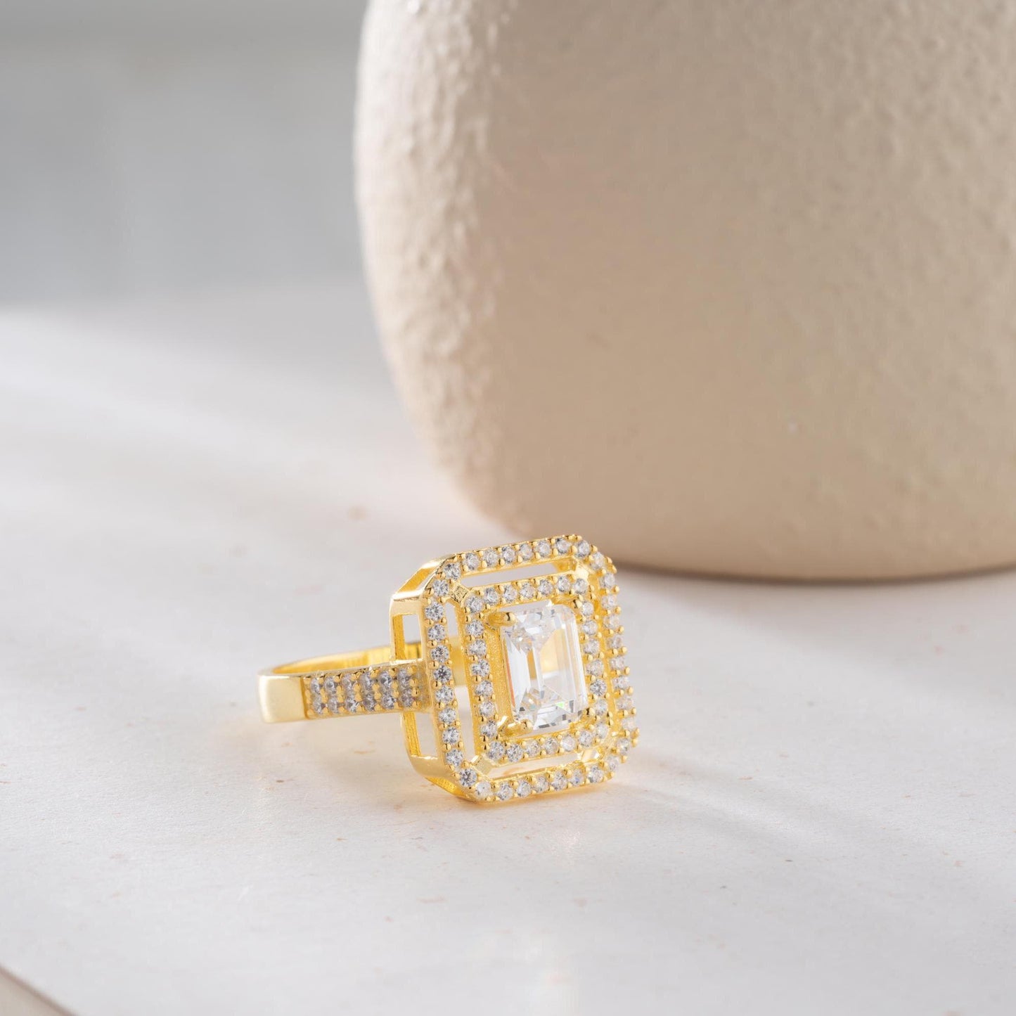 Elegant emerald cut double halo statement ring crafted in 925 sterling silver with cubic zirconia stones, available in silver and gold plated finishes.