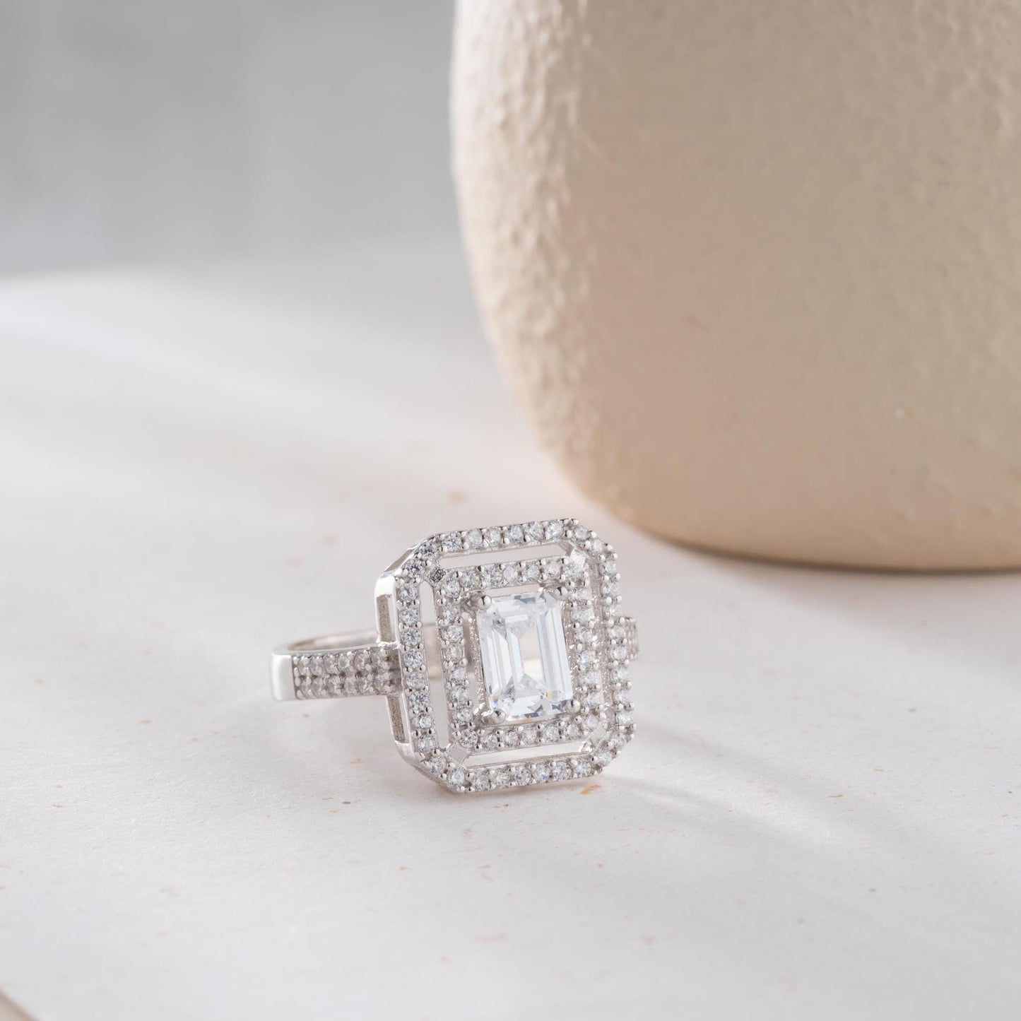 Elegant emerald cut double halo statement ring crafted in 925 sterling silver with cubic zirconia stones, available in silver and gold plated finishes.