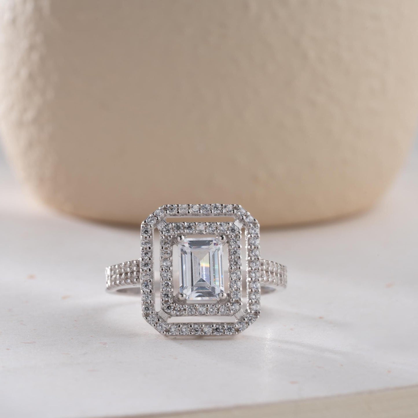 Elegant emerald cut double halo statement ring crafted in 925 sterling silver with cubic zirconia stones, available in silver and gold plated finishes.